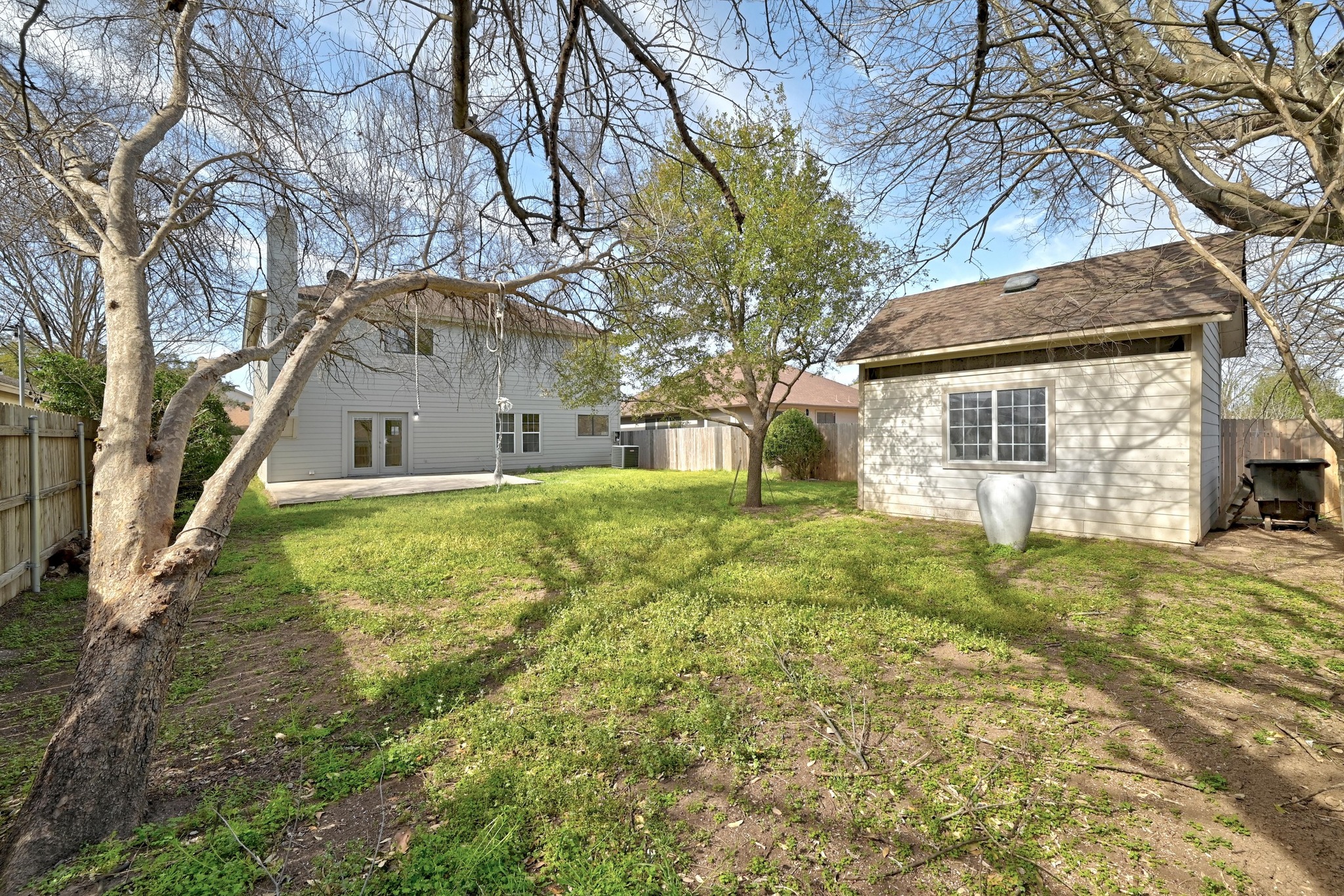 7413 L Marble Ridge Drive Austin, TX 78747 - Photo 24 of 30 Expansive backyard featuring a manicured lawn, a detached storage shed with a window, and a large concrete patio