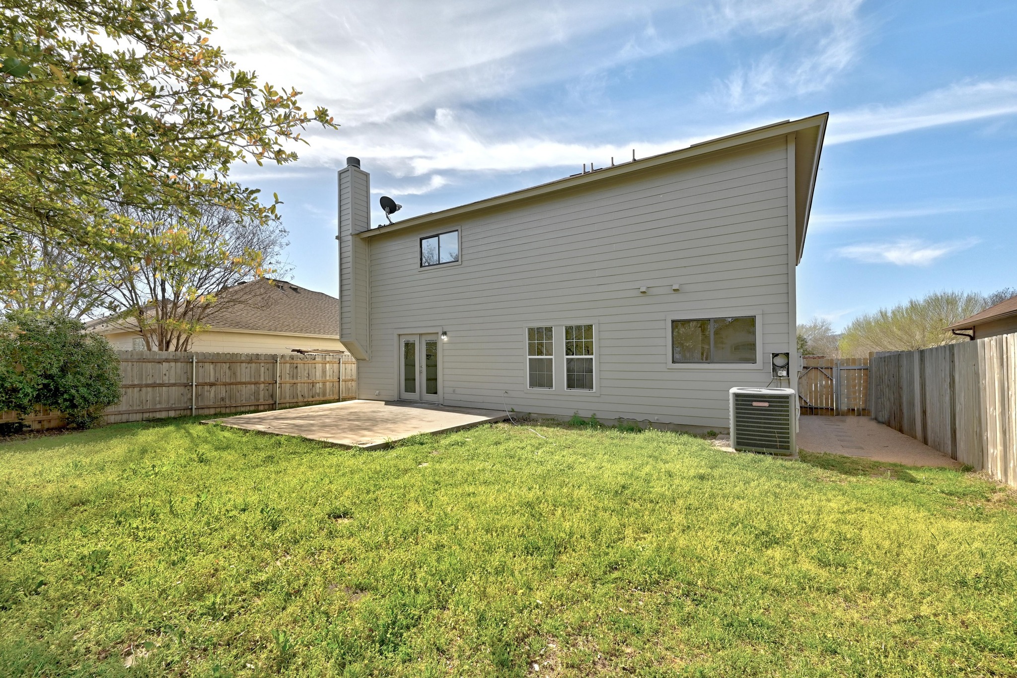 7413 L Marble Ridge Drive Austin, TX 78747 - Photo 25 of 30 Expansive grassy yard featuring a concrete patio, wood privacy fencing, and rear home access via double French doors