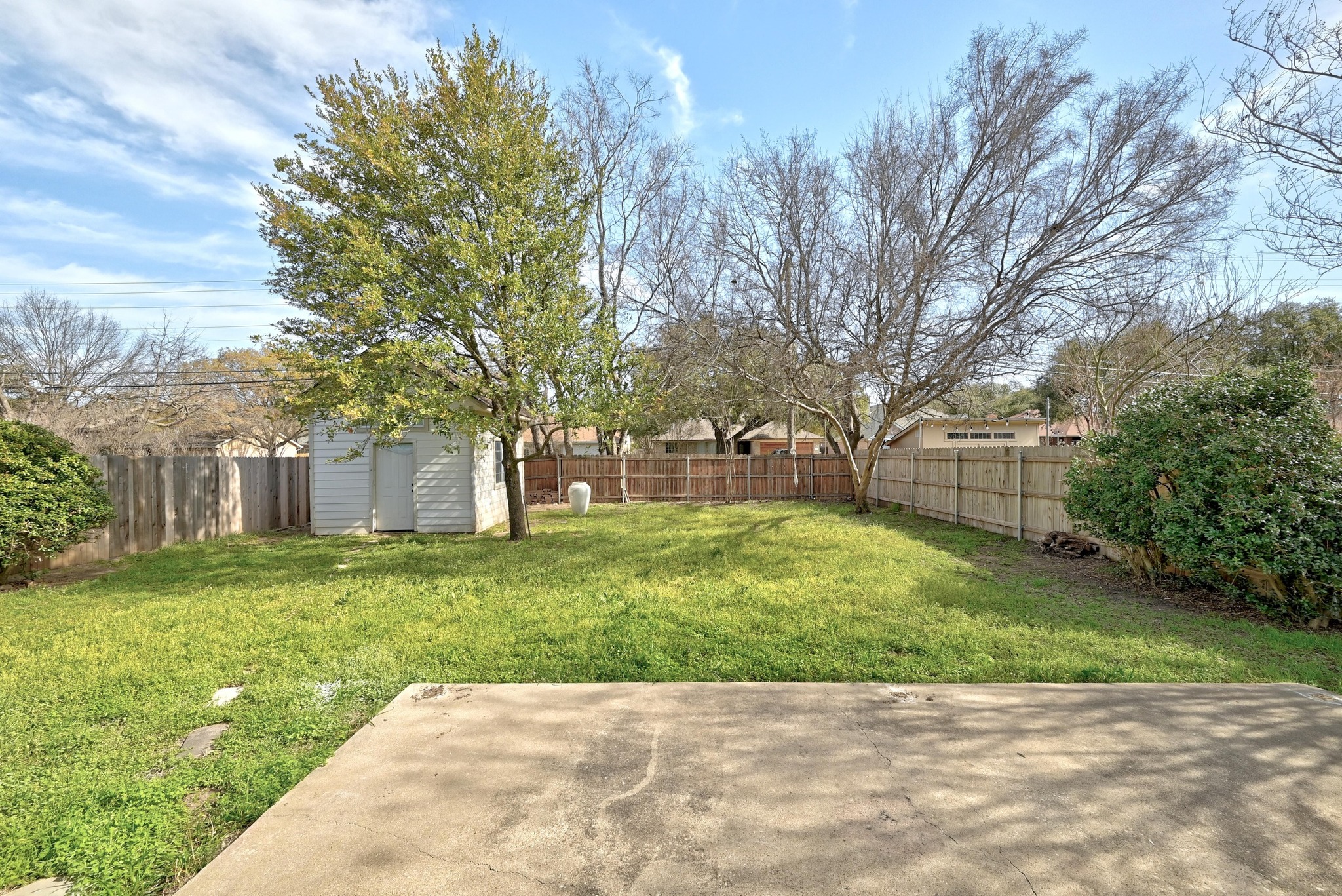 7413 L Marble Ridge Drive Austin, TX 78747 - Photo 26 of 30 Expansive backyard featuring a concrete patio, mature trees, a white storage shed, and a wooden privacy fence