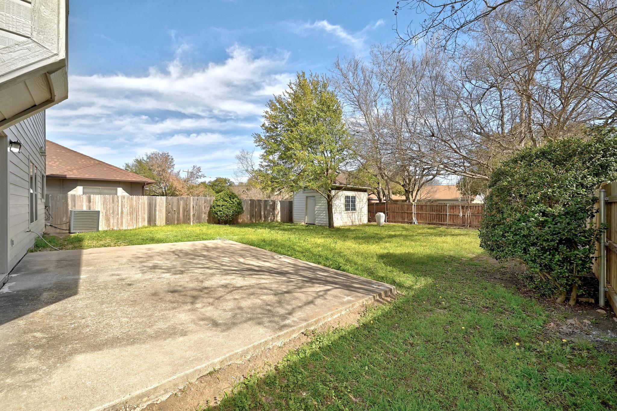 7413 L Marble Ridge Drive Austin, TX 78747 - Photo 28 of 30 Spacious backyard featuring a concrete patio, mature trees, and a storage shed
