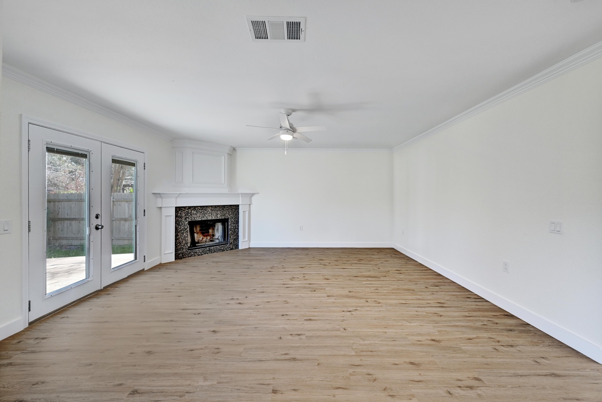 7413 L Marble Ridge Drive Austin, TX 78747 - Photo 6 of 30 Spacious interior featuring wood-finish flooring, a corner fireplace with stone surround, and double glass-panel doors
