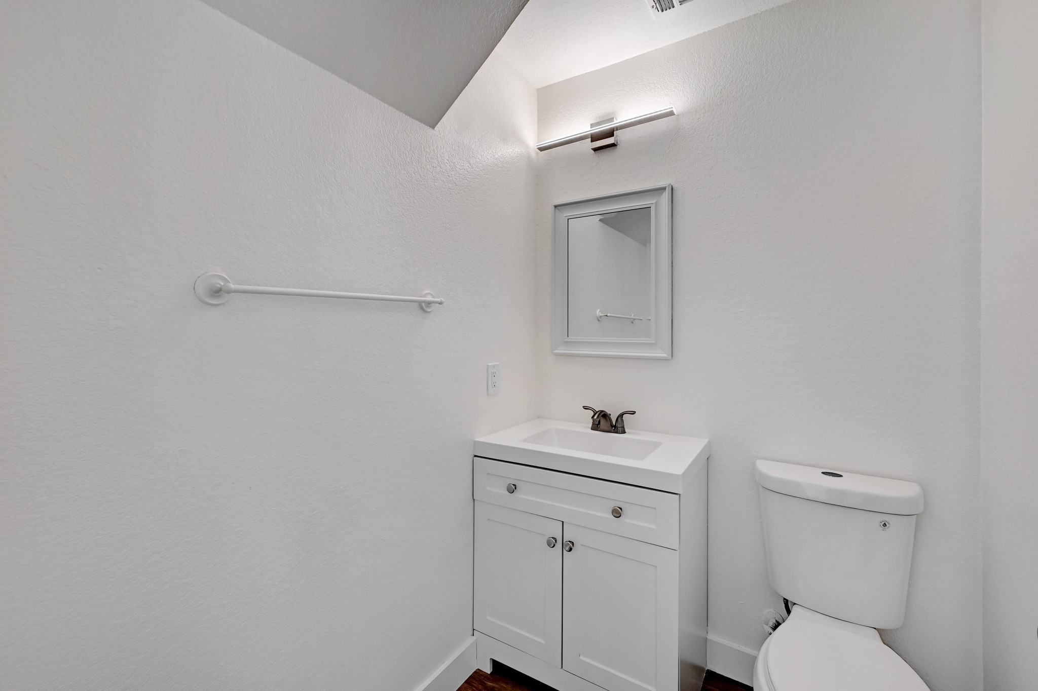 7413 L Marble Ridge Drive Austin, TX 78747 - Photo 7 of 30 Bathroom featuring a white vanity with integrated sink, framed wall mirror, modern wall-mounted light fixture, white toilet, and dark wood-finish flooring
