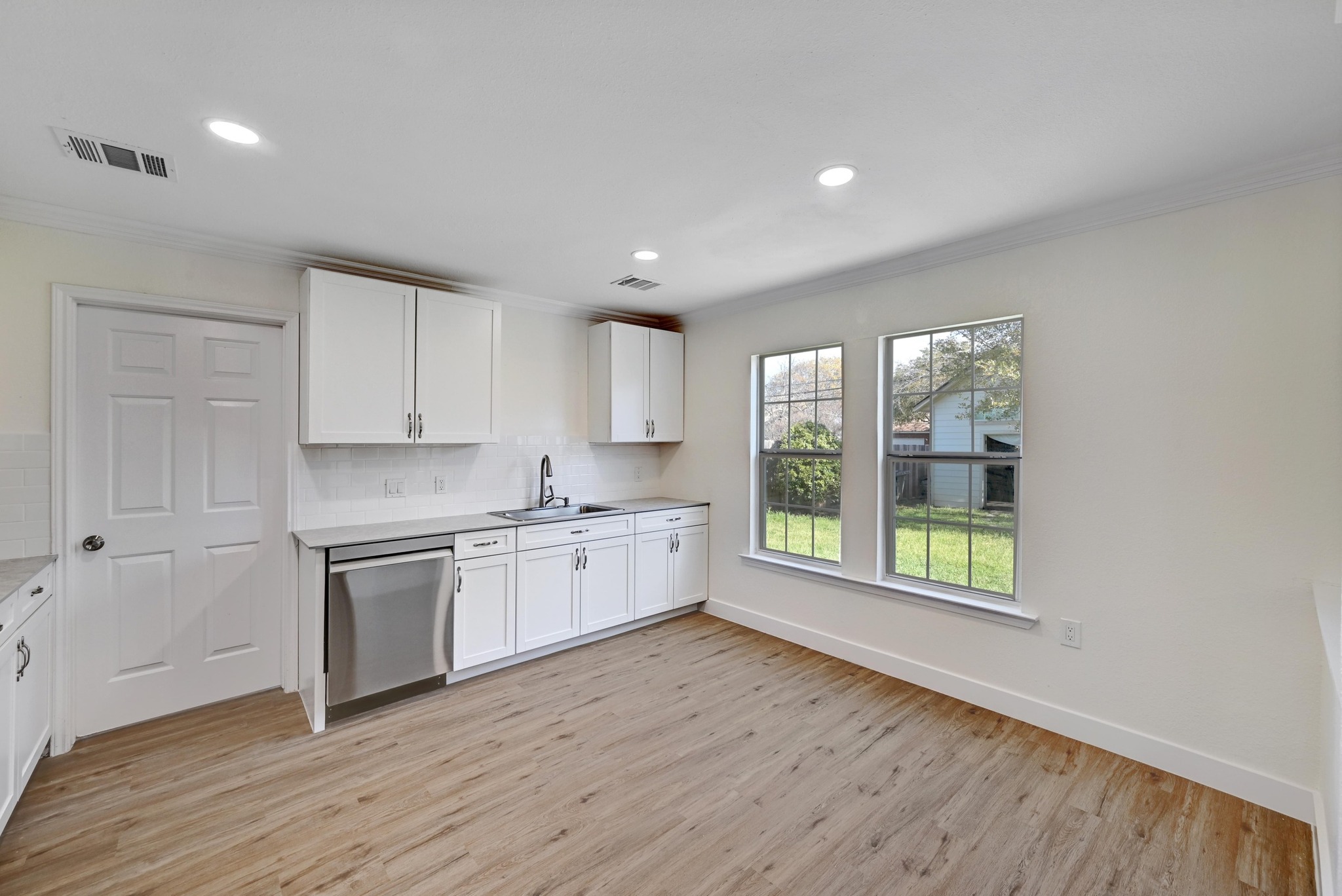 7413 L Marble Ridge Drive Austin, TX 78747 - Photo 8 of 30 Kitchen space featuring white cabinetry, a stainless steel dishwasher, and a grey countertop