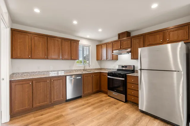a kitchen with granite countertop stainless steel appliances a refrigerator a sink and a stove