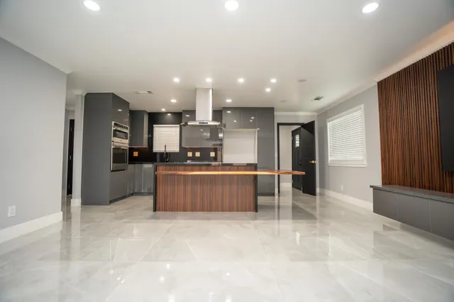 a large kitchen with stainless steel appliances kitchen island granite countertop a refrigerator and a stove top oven