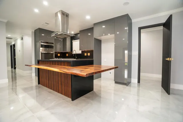 a large kitchen with stainless steel appliances a large counter top and a refrigerator