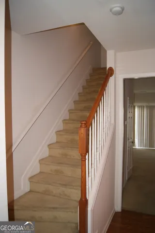 a view of staircase with wooden floor and white walls