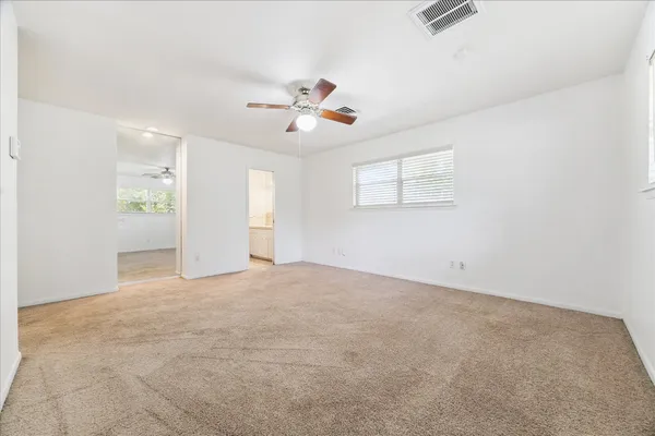an empty room with windows and ceiling fan