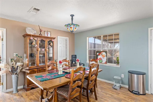 a dining room with wooden floor a chandelier a wooden table and chairs