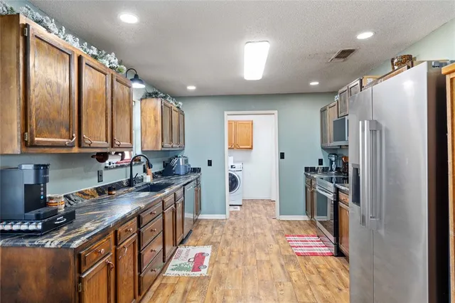 a kitchen with stainless steel appliances granite countertop a refrigerator a stove top oven a sink and dishwasher