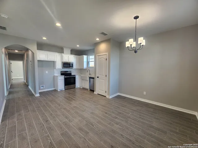 a view of a kitchen with refrigerator and wooden floor