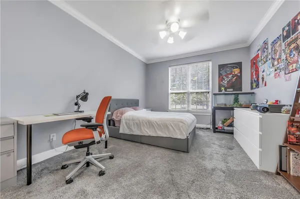 a bedroom with a bed a desk and chair with window