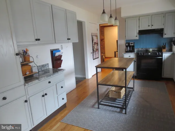 a kitchen with granite countertop a stove a sink and a refrigerator