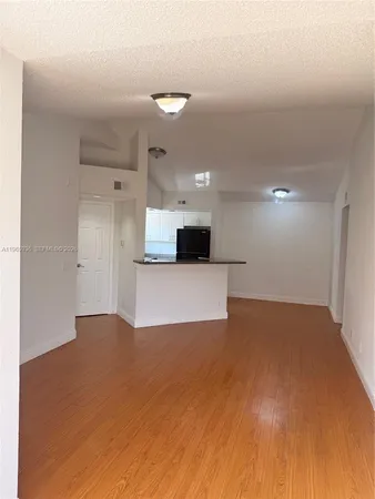 a view of a big room with wooden floor and a kitchen