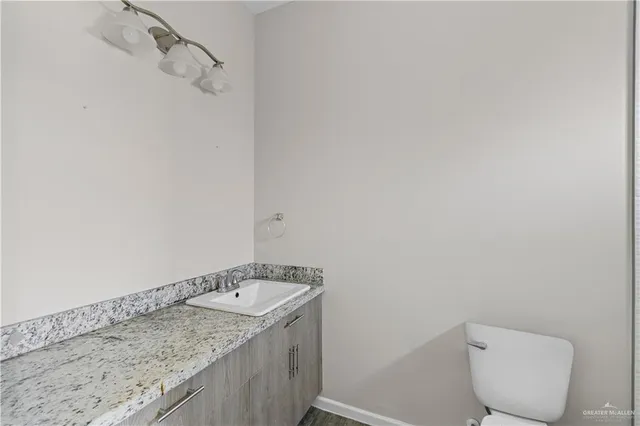 a bathroom with a granite countertop toilet and a sink