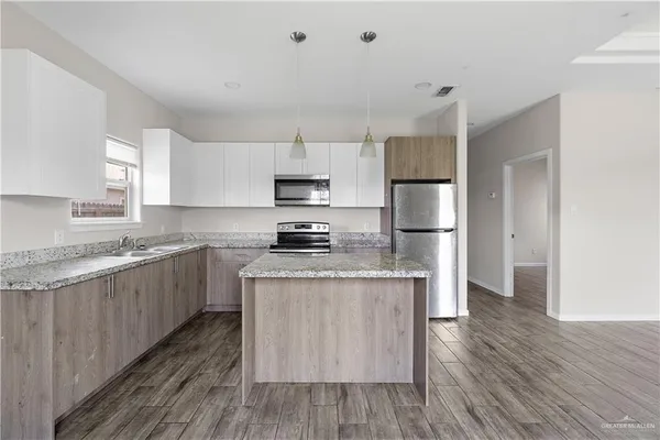 a kitchen with kitchen island wooden floors white cabinets and stainless steel appliances