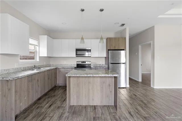 a kitchen with kitchen island wooden floors white cabinets and stainless steel appliances
