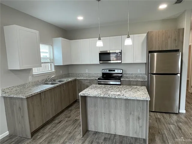 a kitchen with stainless steel appliances granite countertop a refrigerator a sink dishwasher a stove top oven a refrigerator and white cabinets