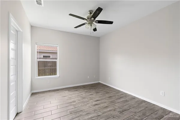 an empty room with wooden floor closet and windows