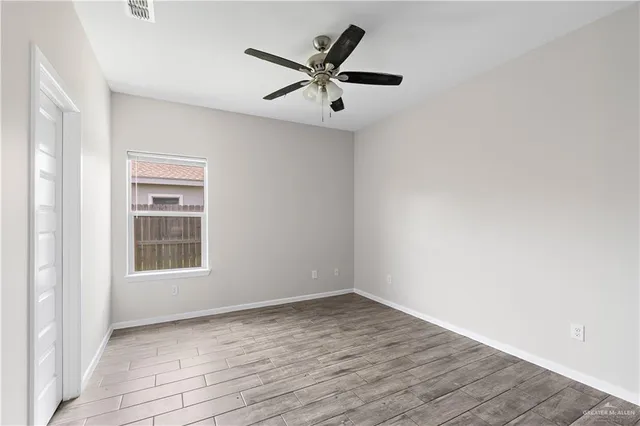 an empty room with wooden floor closet and windows