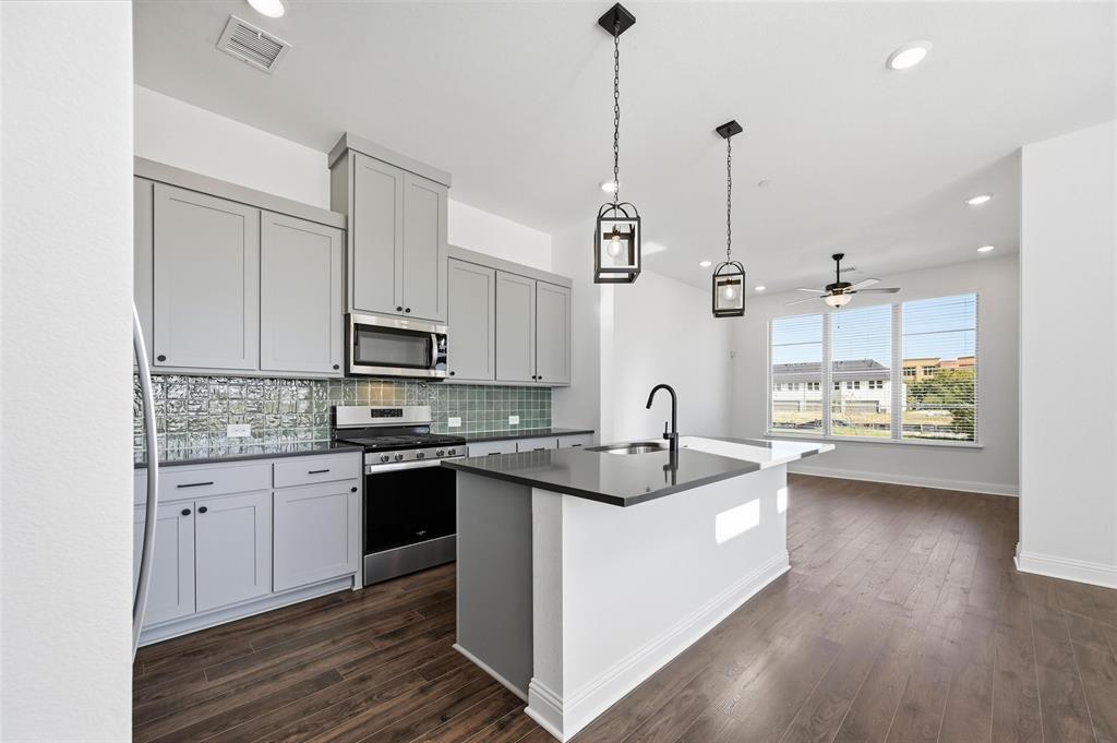 2533 Brunswick Way, Unit 2533 Allen, TX 75013 - Photo 5 of 24 a kitchen with stainless steel appliances granite countertop a sink a stove and a wooden floors