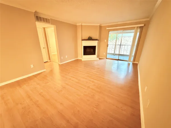 a view of an empty room with a window and kitchen view
