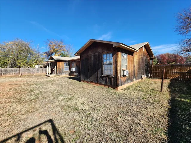 a view of a house with a small yard and wooden fence