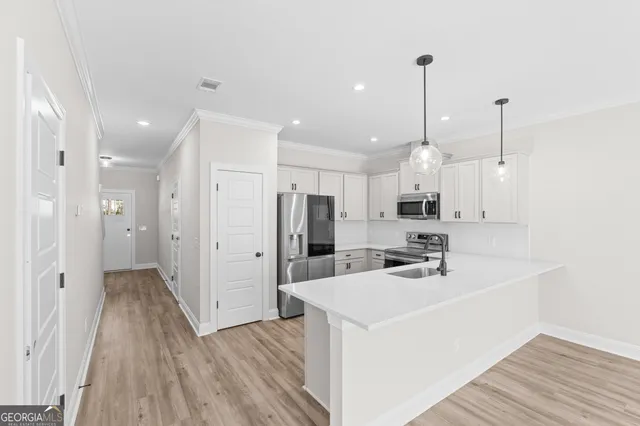 a view of a kitchen with a sink a refrigerator and wooden floor