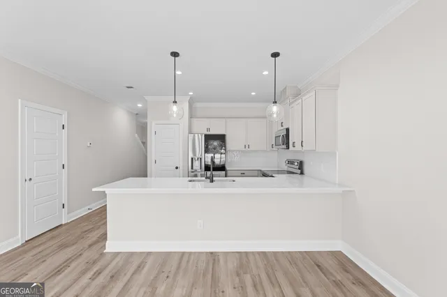 a large white kitchen with a sink dishwasher and a refrigerator with wooden floor