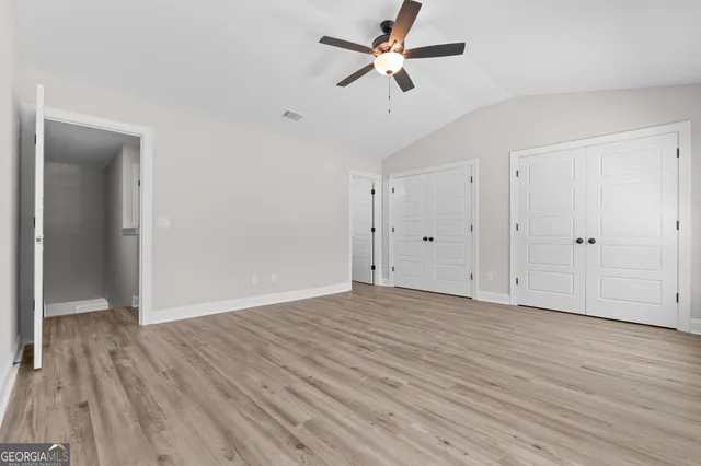 an empty room with wooden floor ceiling fan and window