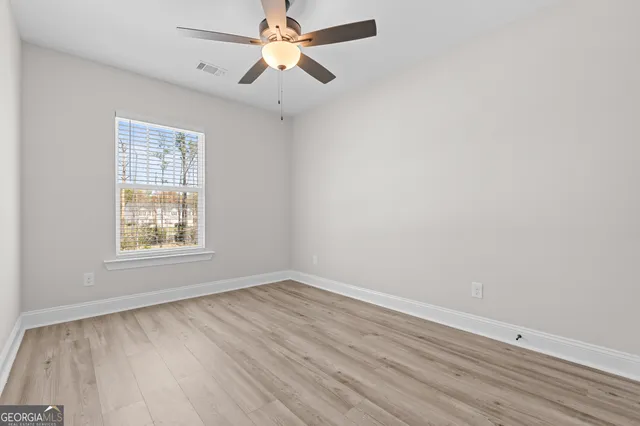 an empty room with a window and a fan
