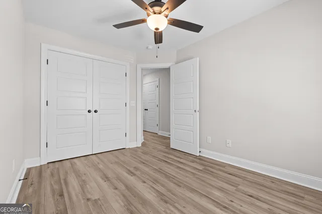 an empty room with wooden floor ceiling fan and windows