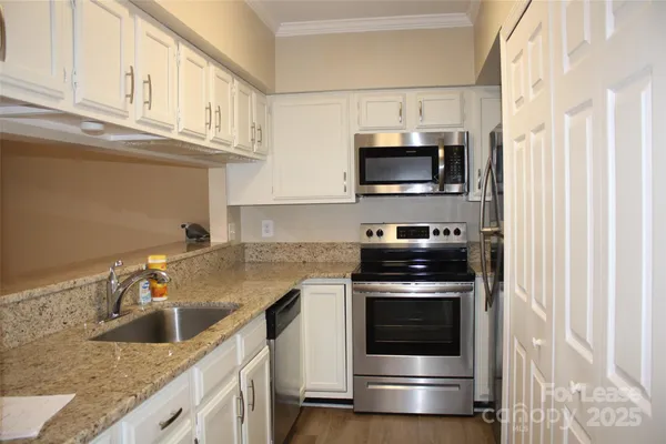 a kitchen with granite countertop a sink a stove and cabinets