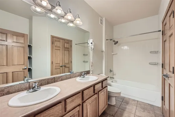 a bathroom with a double vanity sink a toilet a mirror and shower