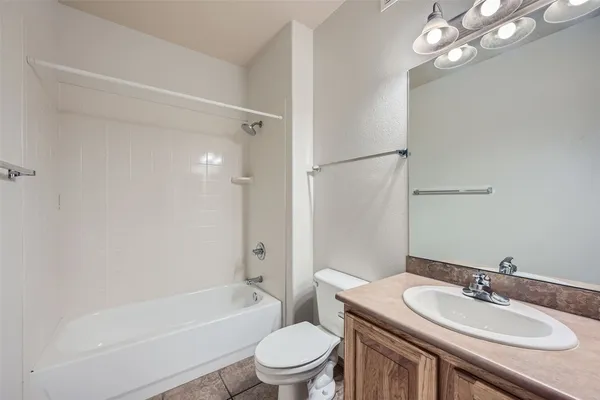 a bathroom with a bath tub sink mirror vanity and toilet