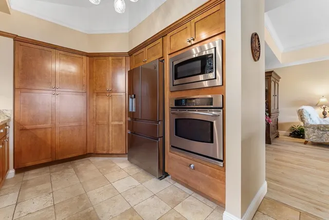 a dining hall with stainless steel appliances granite countertop a lot of counter space furniture and a large window