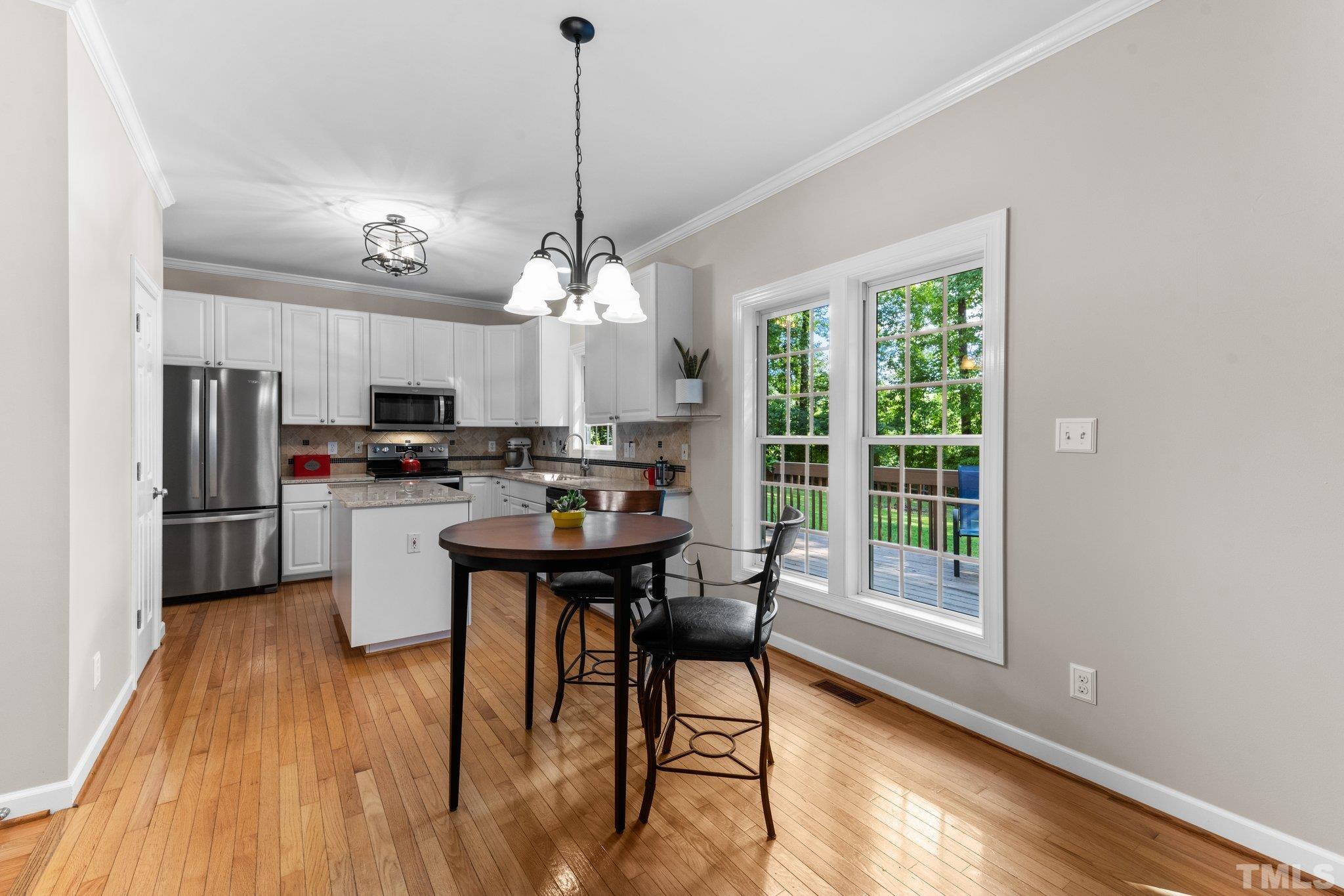 6304 Meerbrook Court Raleigh, NC 27603 - Photo 4 of 30 a kitchen with stainless steel appliances kitchen island granite countertop a refrigerator a stove a sink dishwasher and white cabinets with wooden floor