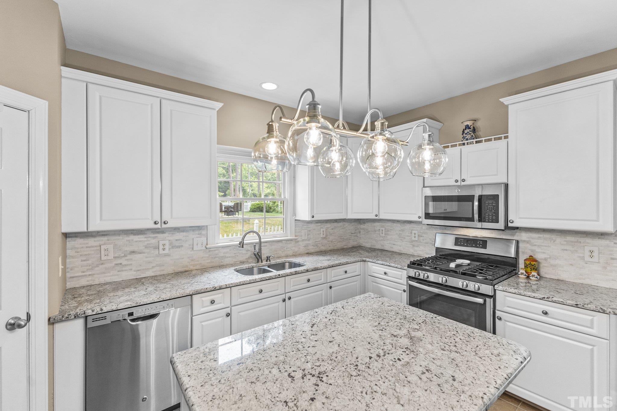 4009 Sunridge Road Raleigh, NC 27613 - Photo 14 of 35 a kitchen with stainless steel appliances granite countertop a sink stove and refrigerator