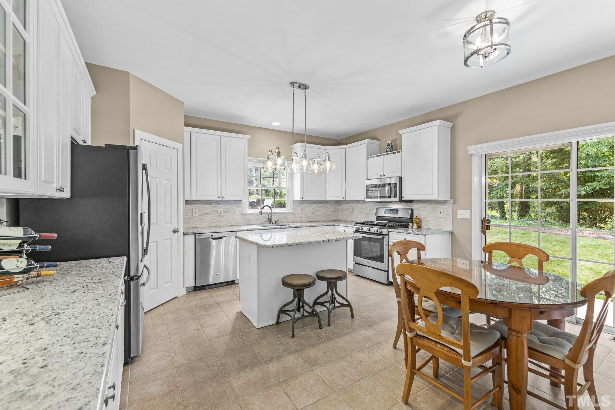 4009 Sunridge Road Raleigh, NC 27613 - Photo 10 of 35 a kitchen with a refrigerator a stove a sink dishwasher with a dining table and chairs
