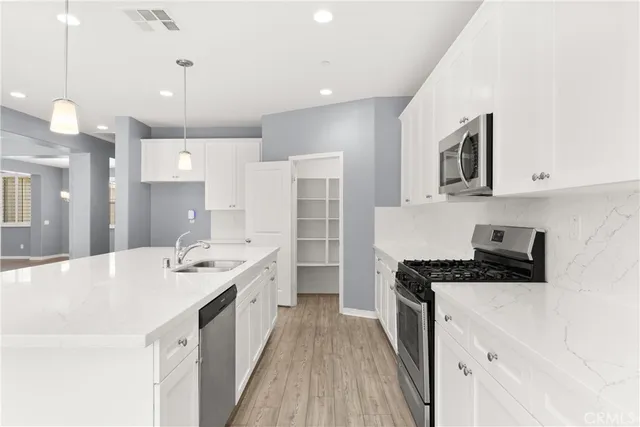 a open kitchen with kitchen island a stove a sink a center island and wooden floor