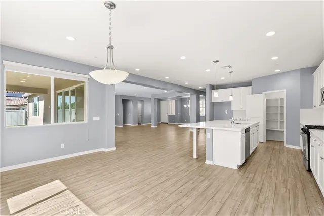 a large kitchen with cabinets chairs and wooden floor