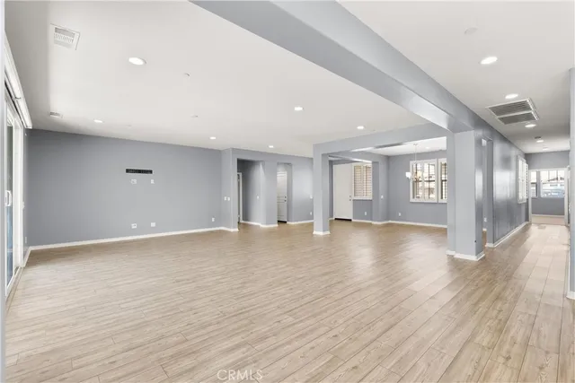 a view of an empty room with window and wooden floor