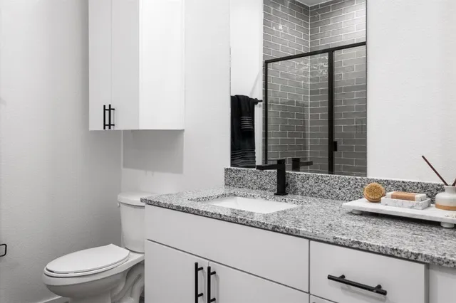 a bathroom with a granite countertop toilet sink and mirror