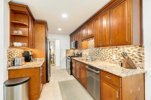 a kitchen with stainless steel appliances granite countertop a sink stove and cabinets