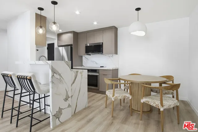 a kitchen with stainless steel appliances kitchen island granite countertop a dining table chairs and sink