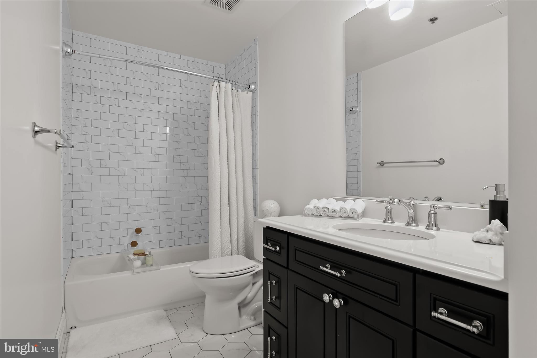 2702 Lighthouse Point East, Unit 522 Baltimore, MD 21224 - Photo 29 of 50 a bathroom with a granite countertop sink toilet a mirror and shower