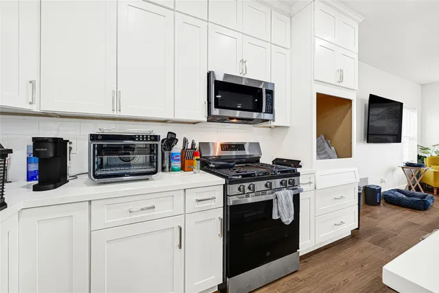 a kitchen with stainless steel appliances granite countertop white cabinets a stove top oven a sink and dishwasher