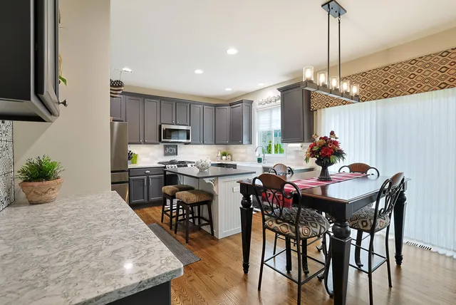 a kitchen with granite countertop kitchen island stainless steel appliances a table and chairs in it