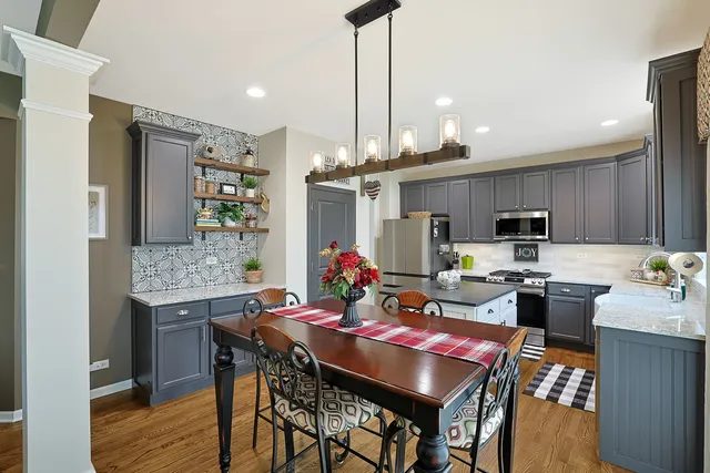 a view of a dining room and livingroom with furniture wooden floor a rug a painting and a chandelier
