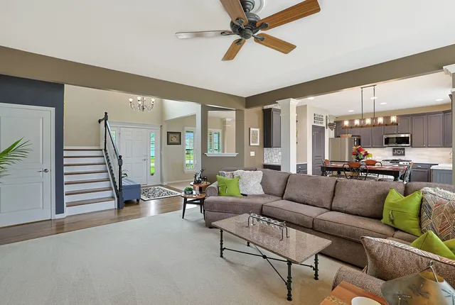 a living room with furniture kitchen view and a large window